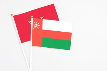 Oman and Isle Of Man stick flags on white background. High quality fabric, miniature national flag. Peaceful global concept.White floor for copy space.