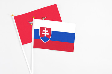 Slovakia and Isle Of Man stick flags on white background. High quality fabric, miniature national flag. Peaceful global concept.White floor for copy space.