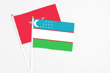 Uzbekistan and Isle Of Man stick flags on white background. High quality fabric, miniature national flag. Peaceful global concept.White floor for copy space.