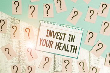 Writing note showing Invest In Your Health. Business concept for Live a Healthy Lifestyle Quality Food for Wellness Scribbled and crumbling papers with thick cardboard above wooden table