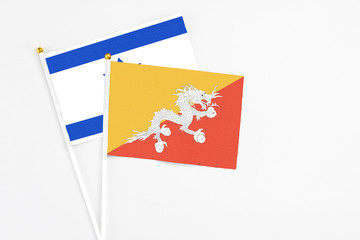 Bhutan and Israel stick flags on white background. High quality fabric, miniature national flag. Peaceful global concept.White floor for copy space.