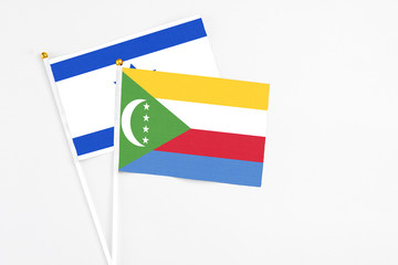Comoros and Israel stick flags on white background. High quality fabric, miniature national flag. Peaceful global concept.White floor for copy space.