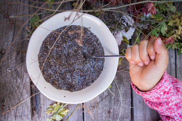Hands holds soaked chia seeds in bowl.
