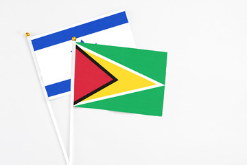 Guyana and Israel stick flags on white background. High quality fabric, miniature national flag. Peaceful global concept.White floor for copy space.