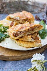 Lobiani - traditional baked Georgian pie with lobio beans and filo puff pastry. On plate with lemon slice, green rucola leaves and garlic. Homemade.