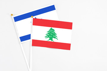 Lebanon and Israel stick flags on white background. High quality fabric, miniature national flag. Peaceful global concept.White floor for copy space.