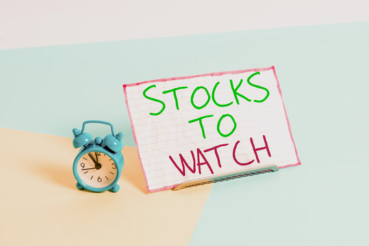 Handwriting text writing Stocks To Watch. Conceptual photo being heavy broker and watch every increase decrease Mini size alarm clock beside a Paper sheet placed tilted on pastel backdrop