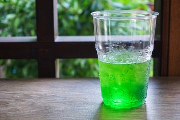 glass of water with lime and ice on wooden background