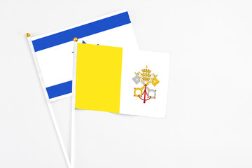 Vatican City and Israel stick flags on white background. High quality fabric, miniature national flag. Peaceful global concept.White floor for copy space.