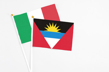 Antigua and Barbuda and Italy stick flags on white background. High quality fabric, miniature national flag. Peaceful global concept.White floor for copy space.