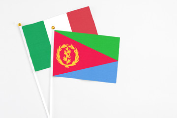 Eritrea and Italy stick flags on white background. High quality fabric, miniature national flag. Peaceful global concept.White floor for copy space.