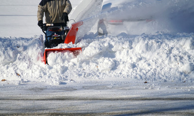 man removing snow on the driveway of the house by snow blower