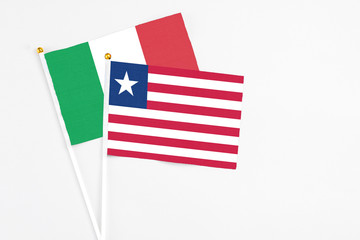 Liberia and Italy stick flags on white background. High quality fabric, miniature national flag. Peaceful global concept.White floor for copy space.