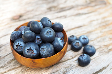 Fresh blueberries in wooden bowls on old wooden table background