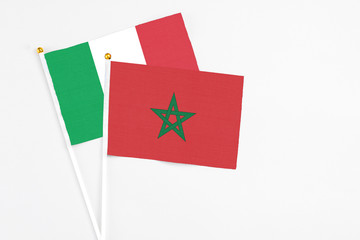 Morocco and Italy stick flags on white background. High quality fabric, miniature national flag. Peaceful global concept.White floor for copy space.
