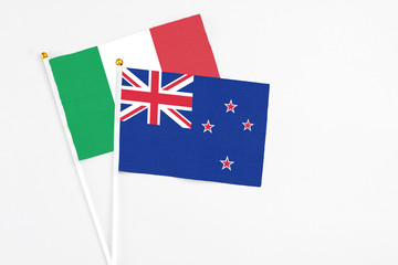 Fototapeta premium New Zealand and Italy stick flags on white background. High quality fabric, miniature national flag. Peaceful global concept.White floor for copy space.