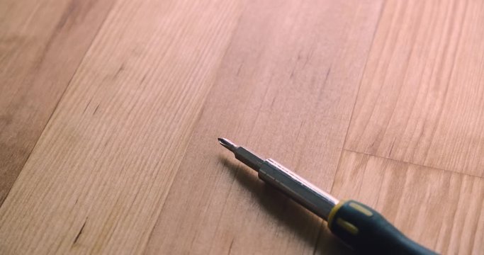 Old crosshead screwdriver on a wooden table with dark shadows. Panning shot