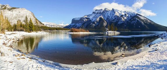 Wide Panoramic Landscape Scenery of Lake Minnewanka With Low Clouds on Snowcapped Mountain Peaks in...