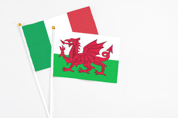 Wales and Italy stick flags on white background. High quality fabric, miniature national flag. Peaceful global concept.White floor for copy space.