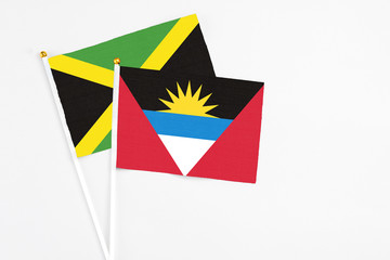 Antigua and Barbuda and Jamaica stick flags on white background. High quality fabric, miniature national flag. Peaceful global concept.White floor for copy space.