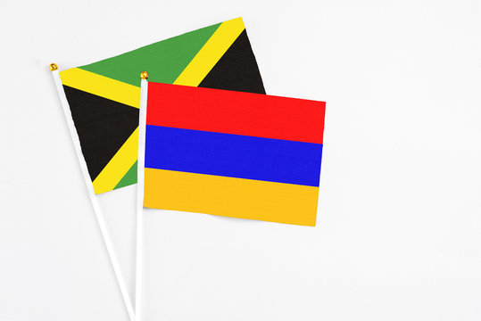 Armenia and Jamaica stick flags on white background. High quality fabric, miniature national flag. Peaceful global concept.White floor for copy space.