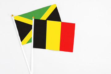 Belgium and Jamaica stick flags on white background. High quality fabric, miniature national flag. Peaceful global concept.White floor for copy space.