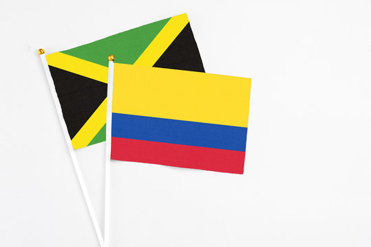 Colombia and Jamaica stick flags on white background. High quality fabric, miniature national flag. Peaceful global concept.White floor for copy space.