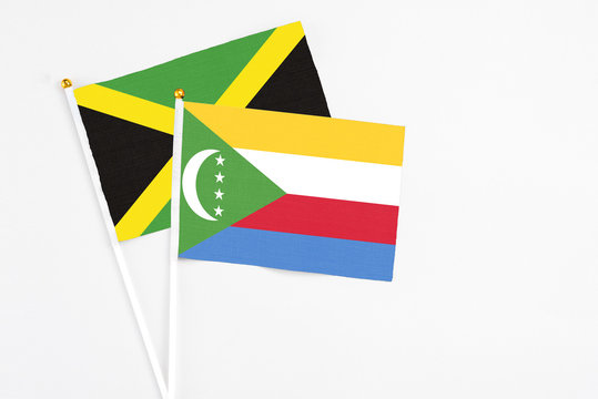 Comoros and Jamaica stick flags on white background. High quality fabric, miniature national flag. Peaceful global concept.White floor for copy space.
