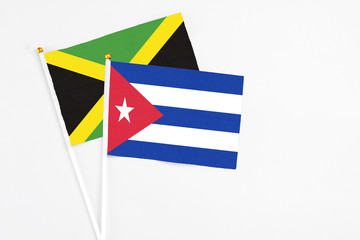 Cuba and Jamaica stick flags on white background. High quality fabric, miniature national flag. Peaceful global concept.White floor for copy space.