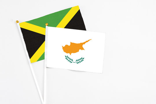 Cyprus and Jamaica stick flags on white background. High quality fabric, miniature national flag. Peaceful global concept.White floor for copy space.