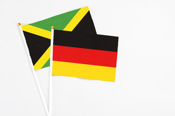 Germany and Jamaica stick flags on white background. High quality fabric, miniature national flag. Peaceful global concept.White floor for copy space.