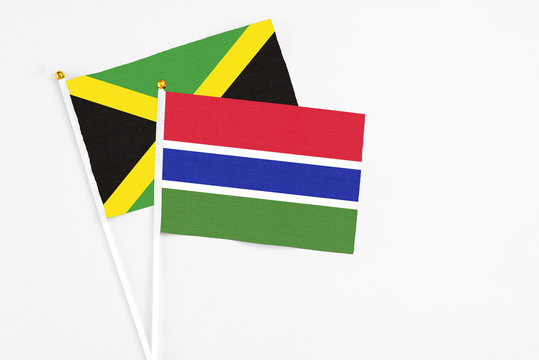 Gambia and Jamaica stick flags on white background. High quality fabric, miniature national flag. Peaceful global concept.White floor for copy space.