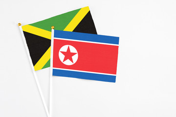 North Korea and Jamaica stick flags on white background. High quality fabric, miniature national flag. Peaceful global concept.White floor for copy space.