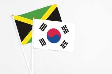 South Korea and Jamaica stick flags on white background. High quality fabric, miniature national flag. Peaceful global concept.White floor for copy space.