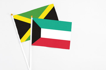 Kuwait and Jamaica stick flags on white background. High quality fabric, miniature national flag. Peaceful global concept.White floor for copy space.