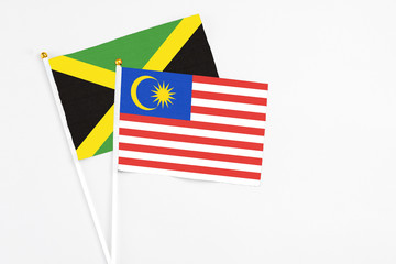 Malaysia and Jamaica stick flags on white background. High quality fabric, miniature national flag. Peaceful global concept.White floor for copy space.