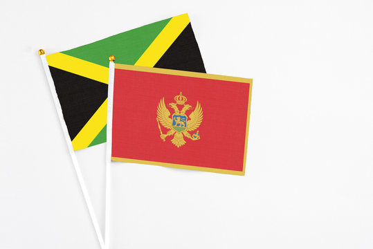 Montenegro and Jamaica stick flags on white background. High quality fabric, miniature national flag. Peaceful global concept.White floor for copy space.