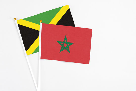 Morocco and Jamaica stick flags on white background. High quality fabric, miniature national flag. Peaceful global concept.White floor for copy space.