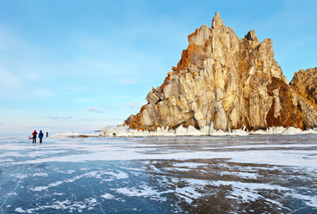 Baikal Lake in the winter. Tourists travel on ice near the Shamanka Rock at Cape Burhan - a natural attraction of Olkhon Island