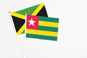 Togo and Jamaica stick flags on white background. High quality fabric, miniature national flag. Peaceful global concept.White floor for copy space.