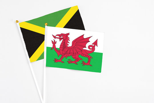 Wales and Jamaica stick flags on white background. High quality fabric, miniature national flag. Peaceful global concept.White floor for copy space.