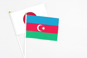 Azerbaijan and Japan stick flags on white background. High quality fabric, miniature national flag. Peaceful global concept.White floor for copy space.