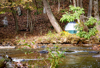 Obraz na płótnie Canvas A tent by a stream in the fall