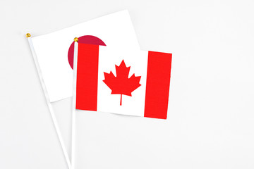 Canada and Japan stick flags on white background. High quality fabric, miniature national flag. Peaceful global concept.White floor for copy space.