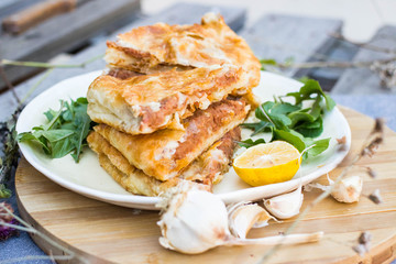 Lobiani - traditional baked Georgian pie with lobio beans and filo puff pastry. On plate with lemon slice, green rucola leaves and garlic. Homemade.