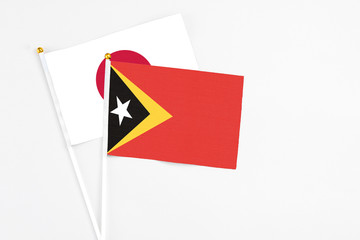 East Timor and Japan stick flags on white background. High quality fabric, miniature national flag. Peaceful global concept.White floor for copy space.