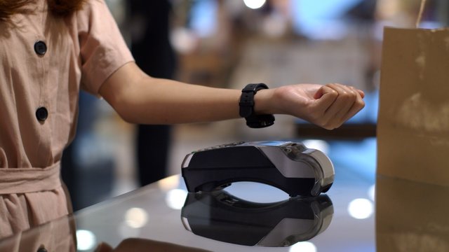 Young woman smart watch contactless payment in shop