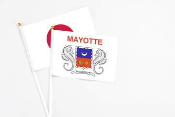 Mayotte and Japan stick flags on white background. High quality fabric, miniature national flag. Peaceful global concept.White floor for copy space.