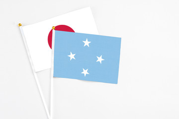 Micronesia and Japan stick flags on white background. High quality fabric, miniature national flag. Peaceful global concept.White floor for copy space.