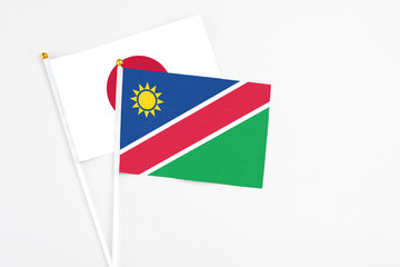 Namibia and Japan stick flags on white background. High quality fabric, miniature national flag. Peaceful global concept.White floor for copy space.